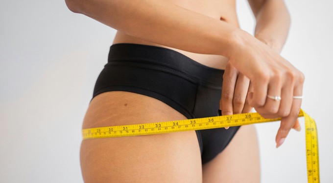 Woman measuring her hips to calculate her body shape